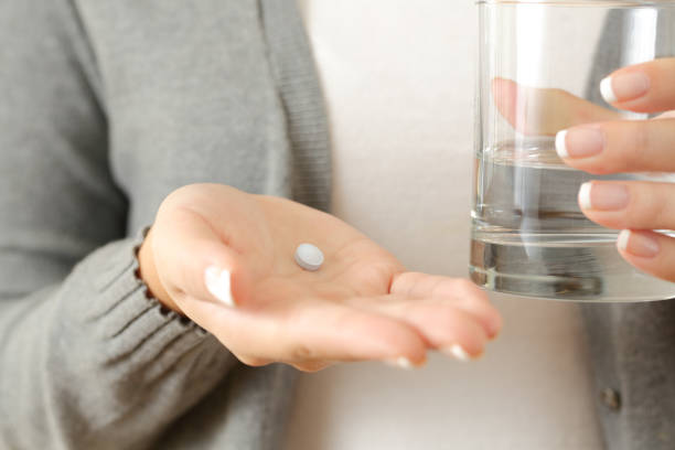 istock Woman hands holding a pill and a water glass 1499681168