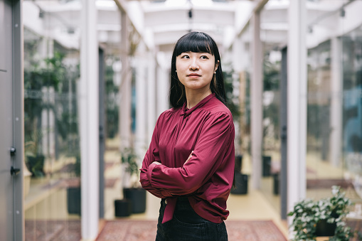 A headshot of a Japanese businesswoman with a positive expression in bright and stylish office room.