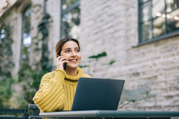 istock Female freelancer making a business call while working at a street cafe 1499682914