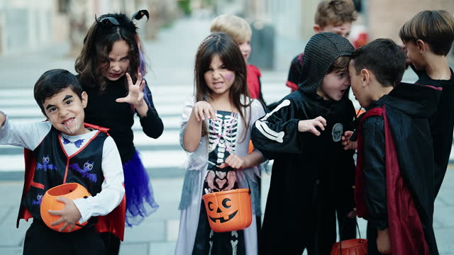 Group of kids wearing halloween costume doing scare gesture at street