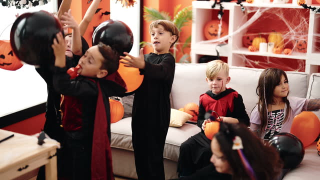 Group of kids wearing halloween costume playing with balloons at home