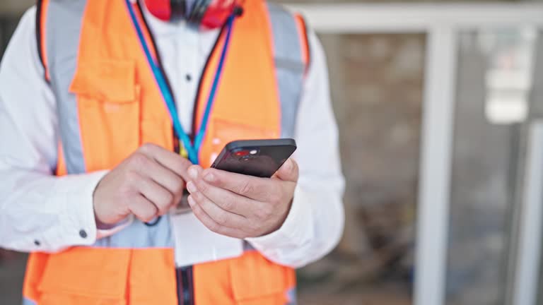 Young caucasian man architect using smartphone at construction site