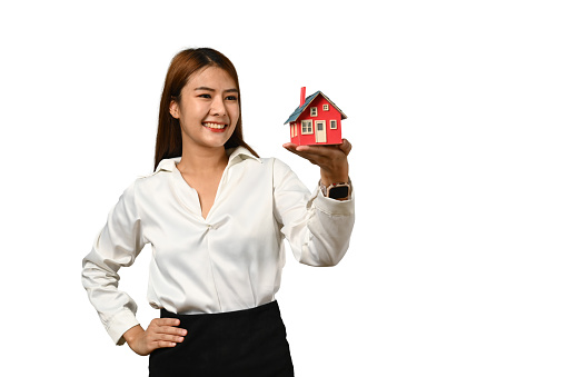 Portrait of beautiful young woman holding house model isolated on white background. Real estate, property and insurance.