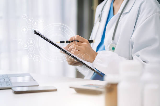 istock female medical doctor's hands write a note and use tablet working. Doctor's working place. Healthcare and medical concept. 1499694353
