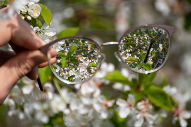 istock Myopia glasses in hand, flowers bloom in focus 1499696343