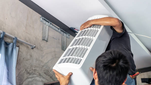 istock Two technicians help each other lift the new air conditioner to install in the room. 1499698085
