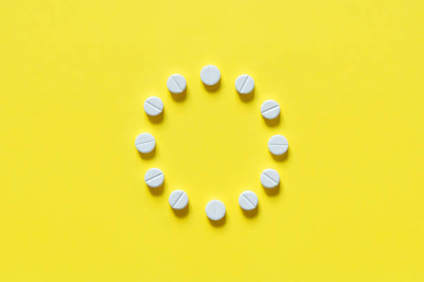 istock White round pills on a yellow background. Copy space, top view, mockup. 1499700553