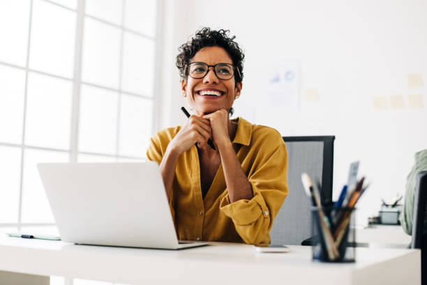 istock Happy graphics designer sitting at her desk thinking about a design 1499701542