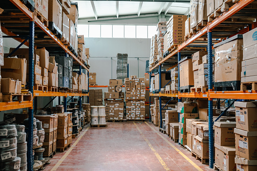 Rows of many shelves with cardboard boxes in storage room of huge distribution warehouse aisle in industrial storage factory background XXXL size