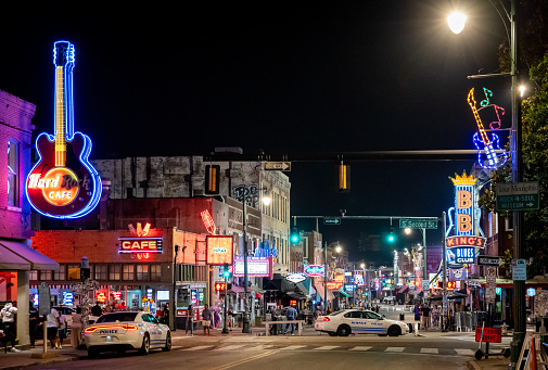 Memphis, Tennessee, USA. 6 June 2023. Police cars parked up by Beale Street at night, Memphis. People walking on the street.