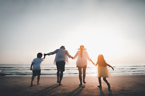 Happy Asian family consisting of father, mother, Son and daughter having fun playing on the beach during summer vacation on the beach. Happy family and vacation concept.