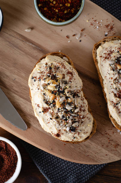Hummus Toast with Rustic Bread, Vegetarian Snack or Breakfast on Wooden Background