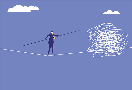 Business man walking a tightrope encounters obstacles.