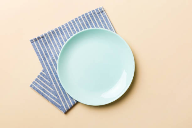 istock Top view on colored background empty round blue plate on tablecloth for food. Empty dish on napkin with space for your design 1499708085