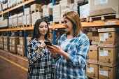 Smart Shopping:  A customer Mother and Daughter Customer Duo Searching Goods Stock in Retail Warehouse with Smartphones