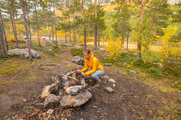istock Young woman making fire at campground, she warms up 1499708281