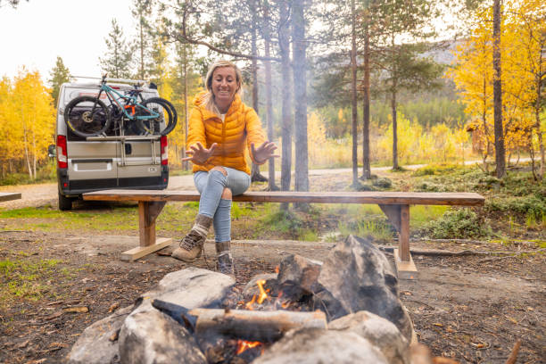 She makes a camp fire in nature, her van parked behind, the real camping lifestyle. Solitude in nature