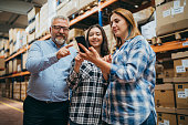 Smart Shopping:  A customer family using a smartphone while scrolling through goods searching stock on the online shopping website or app in a retail warehouse market mall