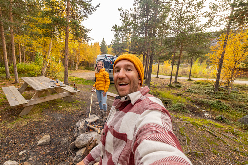 They make a camp fire in nature, their van parked behind, the real camping lifestyle. Solitude in nature