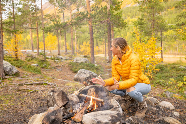 istock Young woman making fire at campground, she warms up 1499708984