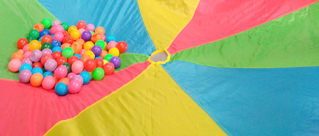 Fun activities for kindergarten children, one of which is a parachute game with the balls that will be thrown into the air.