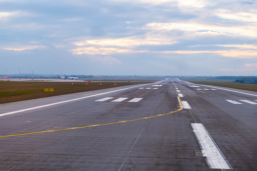 A long, straight runway stretches into the distance at the airport, with aircraft markings and clear paths for takeoff and landing