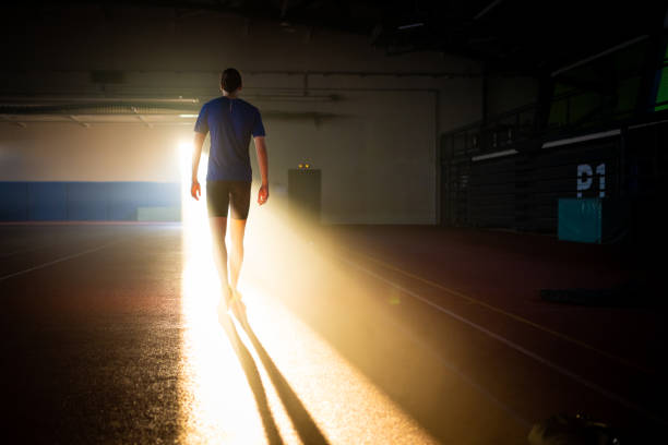 Rear view of athlete young man walking in sports hall.