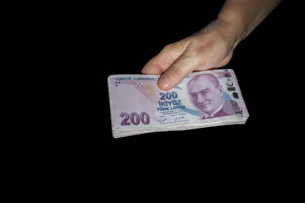 Hand holding a large number of 200 Turkish liras Top angle of hands holding many 200 Turkish lira banknotes with space for text on background black para birimi stock pictures, royalty-free photos & images