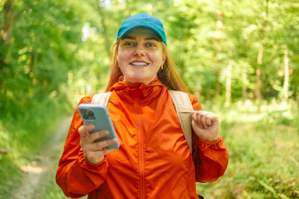 istock Attractive fit girl tourist with a backpack using mobile phone while walking in the forest, doing hiking. Using gadgets while hiking. 1499715641
