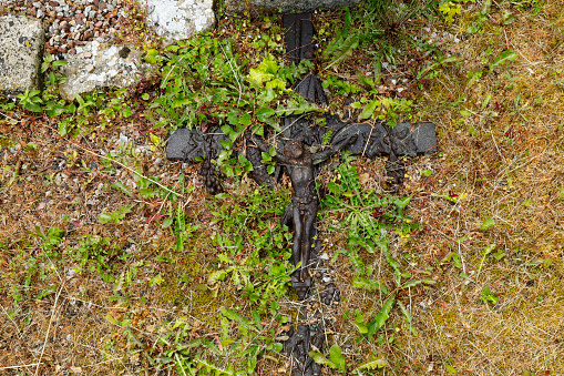 Old cross overgrown with dandelions in a cemetery
