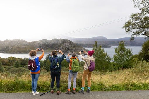 A rear view of four mature women  enjoying an a trip in the Scottish Highlands to a place called Loch Torridon. They have stopped at a viewpoint to take in the breathtaking view across the valley.