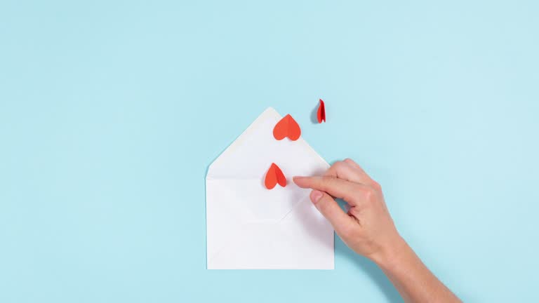 Red heads of small roses emerge from white envelope. Love messages concept.