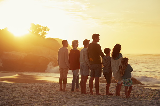 Shot of a family and their kids spending the day at the beach during sunset