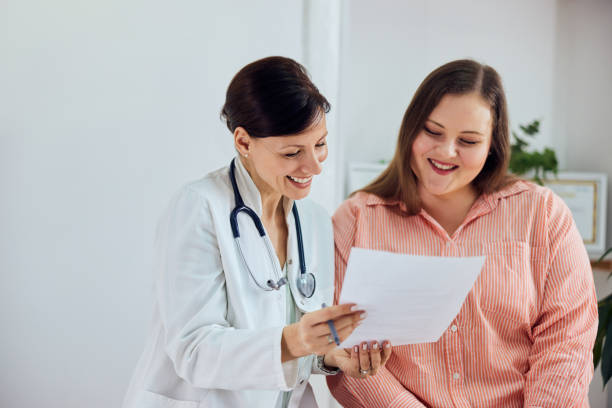 A smiling female nutritionist showing good progress results to a happy overweight patient. A happy overweight woman is satisfied with her weight loss program results and sitting with a female nutritionist. 30s 40s activity adult stock pictures, royalty-free photos & images