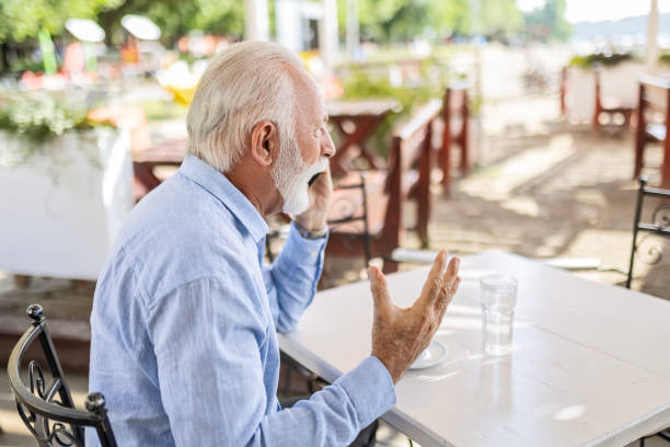 istock Senior man yelling in outdoor cafe using smart phone 1499725268