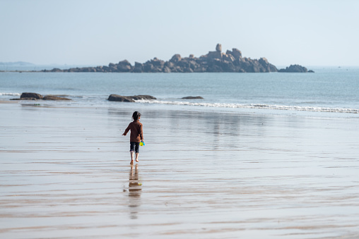 An Asian girl running barefoot on the beach