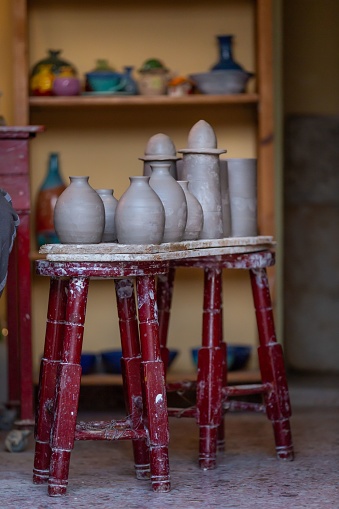 A vertical of a workshop with ceramic jars on an antique stool