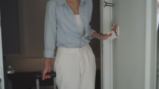 Asian businesswoman with luggage entering to the room of hotel after opening the security door by using keycard and turn on the light in the room of hotel