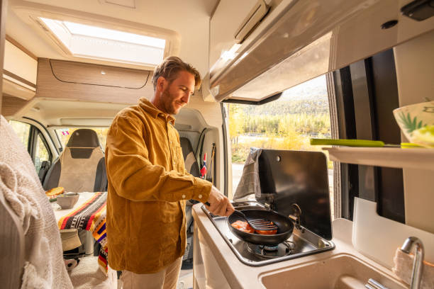 Man preparing food inside his camper van. Camping concept