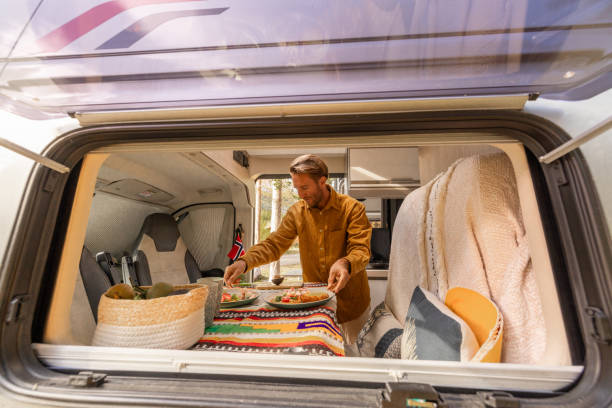 Man preparing food inside his camper van. Camping concept