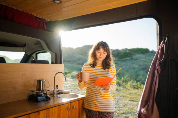 istock Woman reading book and drinking coffee in camper van 1499734701
