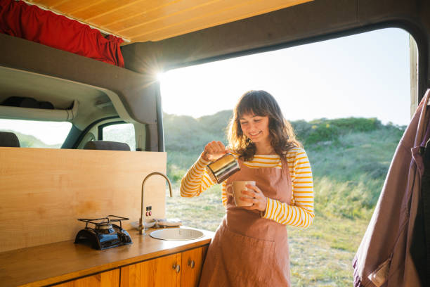 Woman in apron drinking coffee in  the camper van