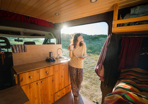 istock Woman reading book and drinking coffee in camper van 1499735060