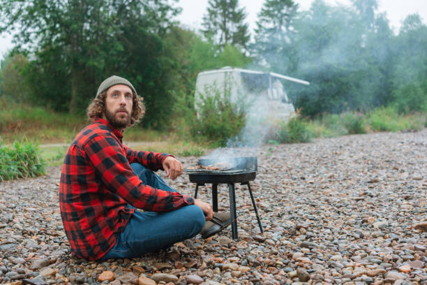 istock Man in red checked shirt barbecuing near the river in Norway 1499736521