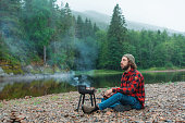 Man in red checked shirt barbecuing near the river in Norway