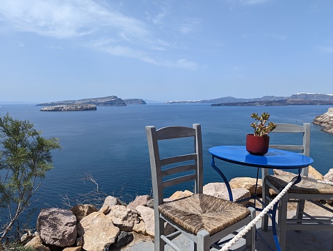 Pair of chairs and a round blue table looking out over the Mediterranean Sea on Santorini.