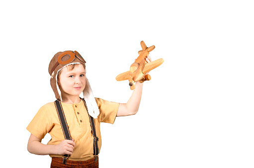 isolated object boy of primary school age holds a toy wooden plane in his hands