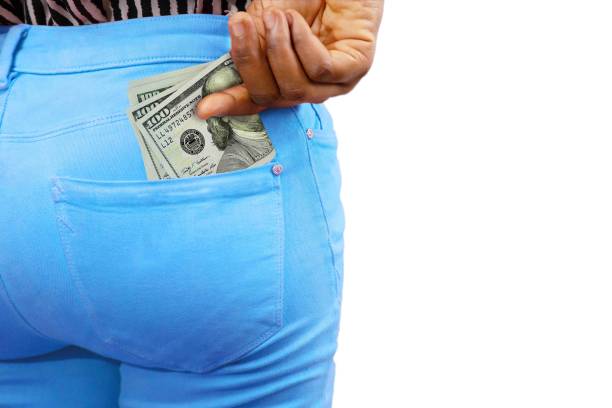 Black lady putting few US dollar notes into her back pocket. Removing money from pocket, hold money