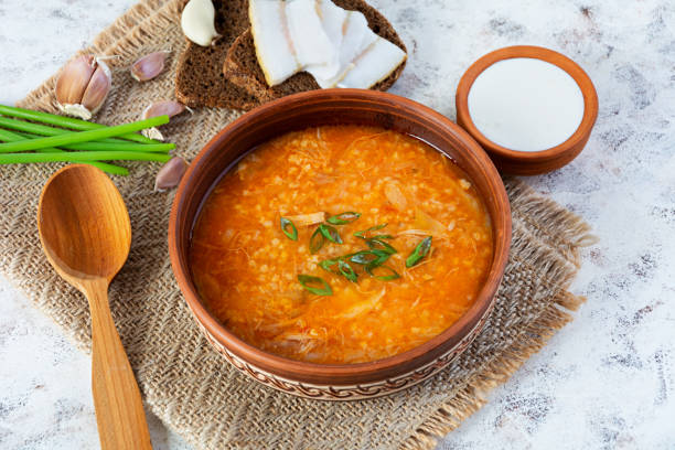 istock Cabbage soup in bowl with green onion, bread and salo on white background 1499747561