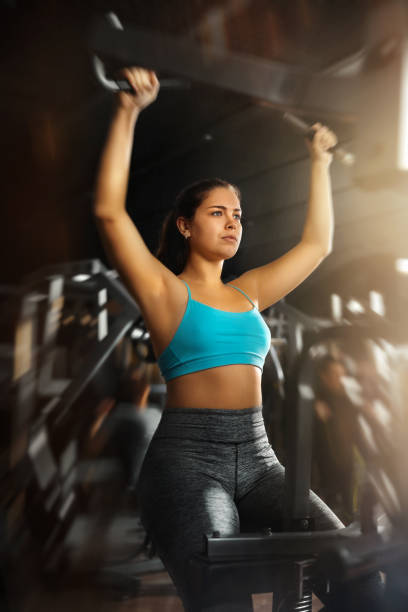 istock Sporty girl performing lever pull down on gym machine 1499748982